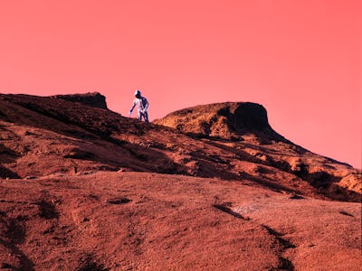 Astronaut walking on red Mars rock