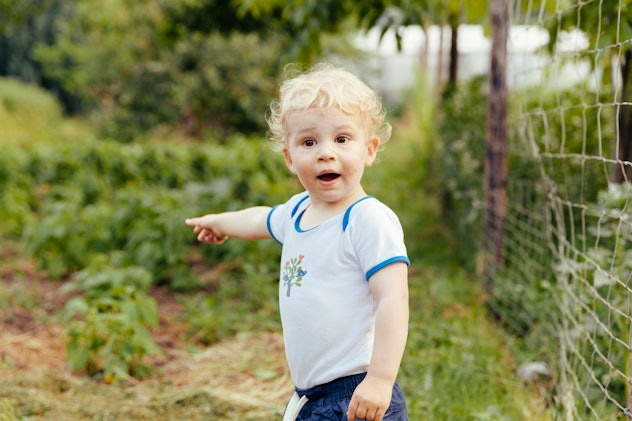 cute toddler boy in a vegetable garden pointing to something in the distance in a round up of boy na...