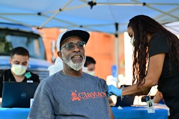 DENVER, CO - AUGUST 5: Janaldo Mims, 64, left, gets a COVID-19 booster shot from Medical Assistant A...