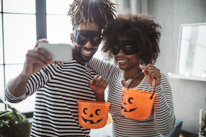 A couple takes a photo for Instagram in their couples Halloween costume.