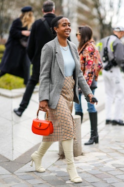 street style woman wears a skirt and white boots