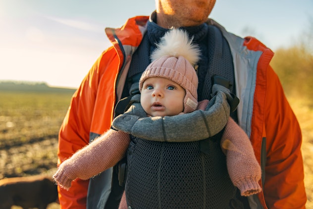 a cute, very little baby in a baby carrier in an article about girl names that start with C