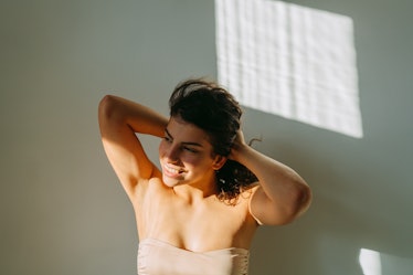 young woman plays in her hair as she poses next to an open window and considers her sept. 19, 2022 w...