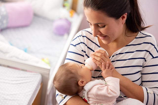 Loving Latin American mother at home feeding a bottle to her baby - motherhood concepts