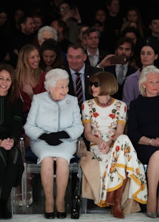 Queen Elizabeth II sits next to Anna Wintour (right) as they view Richard Quinn's runway show 