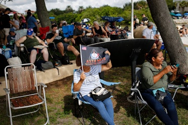 A woman uses an Artemis flag as cover from the sun as she waits for the launch of the Artemis I unma...