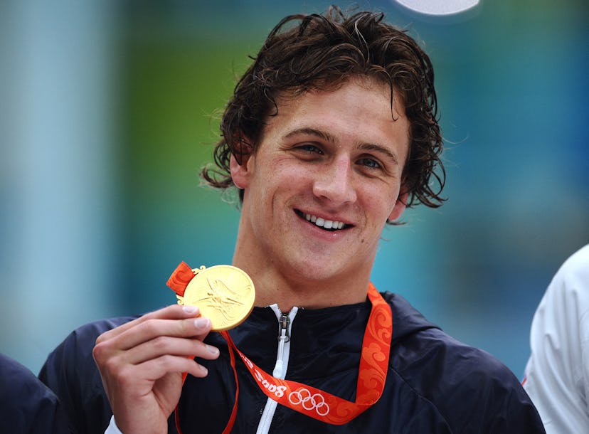 US swimmer Ryan Lochte poses with his gold medal on the podium during the medal ceremomy after the m...