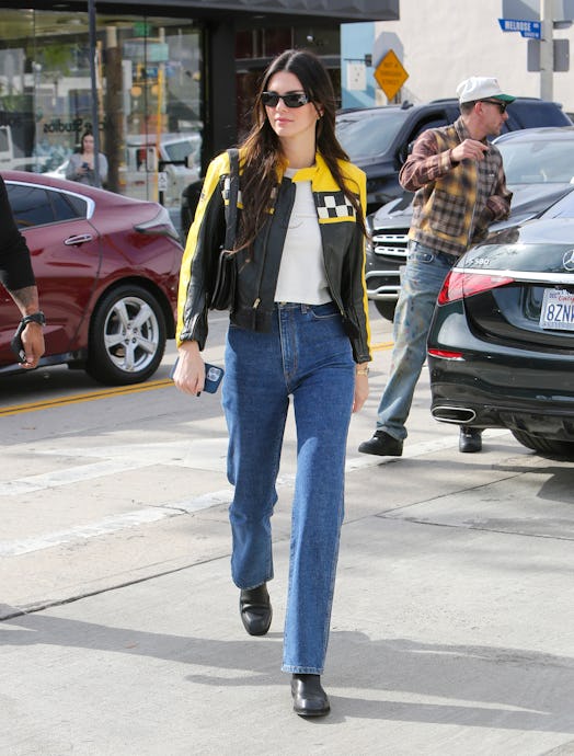 Kendall Jenner wears a black and yellow moto jacket with jeans and a white t-shirt