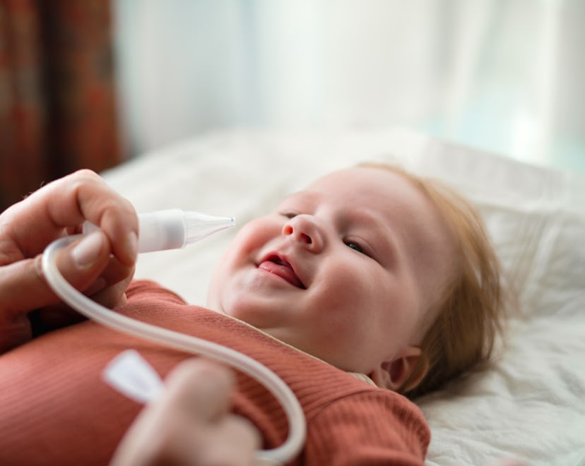 Father using nasal aspirator for his baby at home in an article about nasal aspirator brain damage