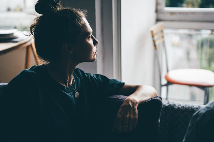 Sad and depressed woman sitting on sofa at home.