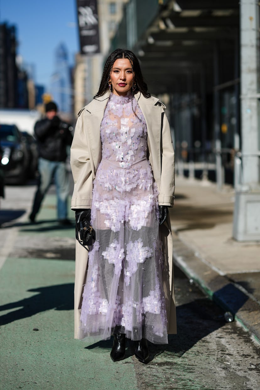 A runway show guest wearing a sheer spring dress in winter.