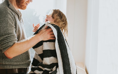 Father towel drying his young daughter after a bath in an article about viral hives in children