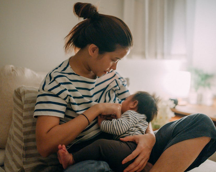 A mother breastfeeding baby at home, an example of how sleep training and breastfeeding can work.