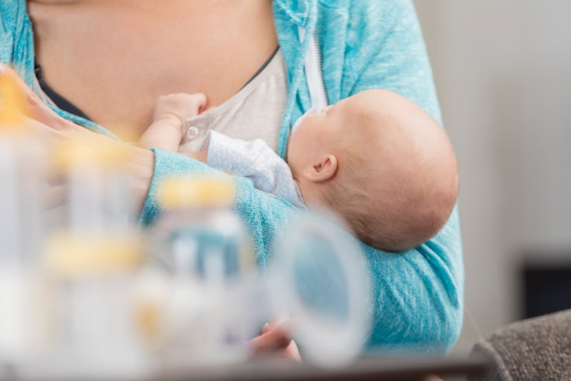 Mom holding a newborn with a breast pump in the foreground.
