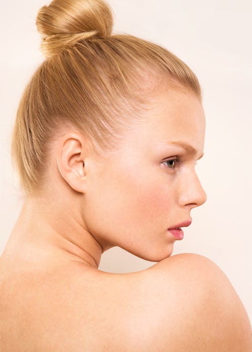 A blonde woman with her hair in a top knot bun poses for a profile headshot