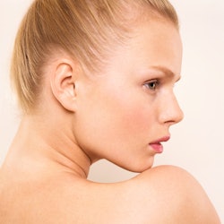 A blonde woman with her hair in a top knot bun poses for a profile headshot