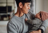 Smiling Asian father shot holding his newborn baby daughter for article about best valentine's day g...