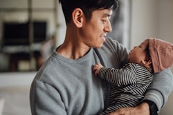 Smiling Asian father shot holding his newborn baby daughter for article about best valentine's day g...