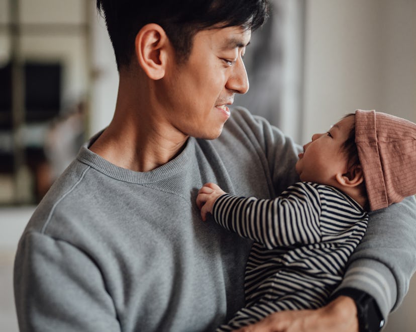 Smiling Asian father shot holding his newborn baby daughter for article about best valentine's day g...