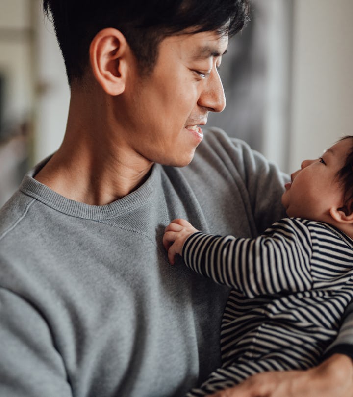 Smiling Asian father shot holding his newborn baby daughter for article about best valentine's day g...