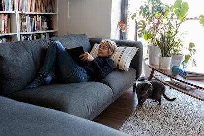 Woman reading book on couch in a story about what to expect after a hysterectomy