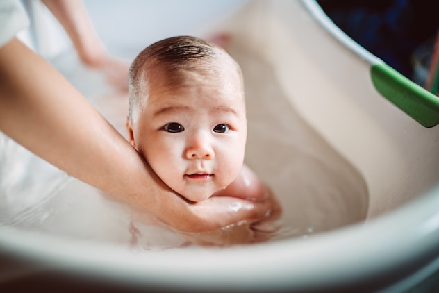 Adorable new born baby smiling joyfully at the camera during bath in article about aquarius boy name...