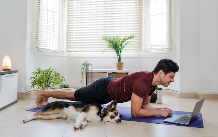 man is taking online fitness classes from laptop at home