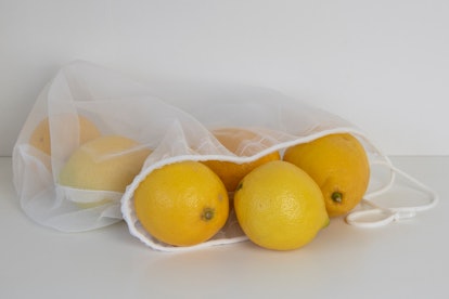 Close-up of lemons in cloth bag, white surface