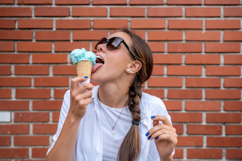 Young woman licking a new fantasy flavour of blue ice cream