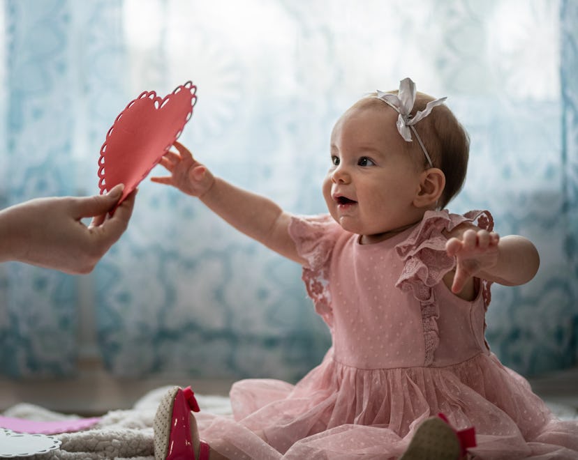 Baby girl reaching for a paper heart, in a story about how to celebrate baby's first Valentine's Day