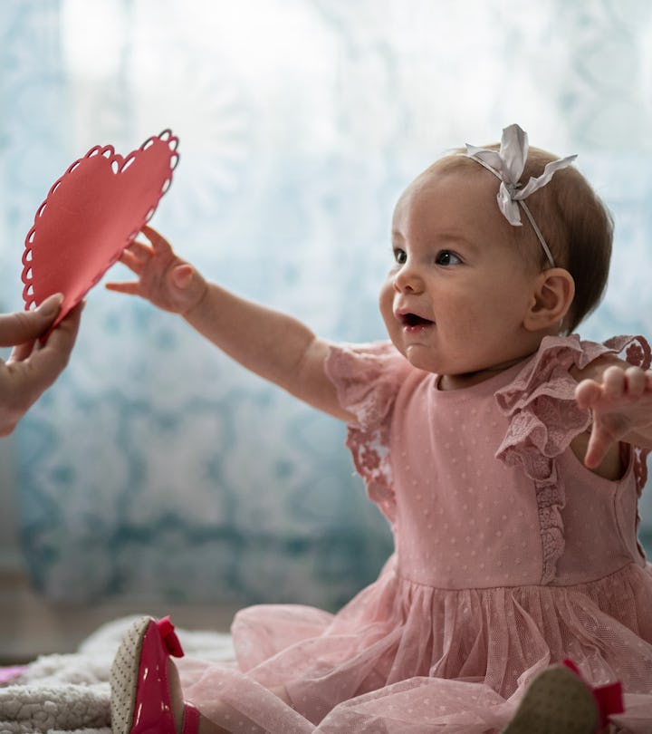 Baby girl reaching for a paper heart, in a story about how to celebrate baby's first Valentine's Day