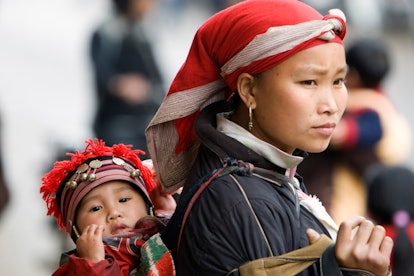 Red Dzao woman with baby on back in sling hill tribe Sapa Vietnam. (Photo by: Andrew Woodley/Educati...