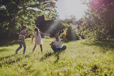 Beautiful smiling brother and sister having fun with dad in nature on a sunset.