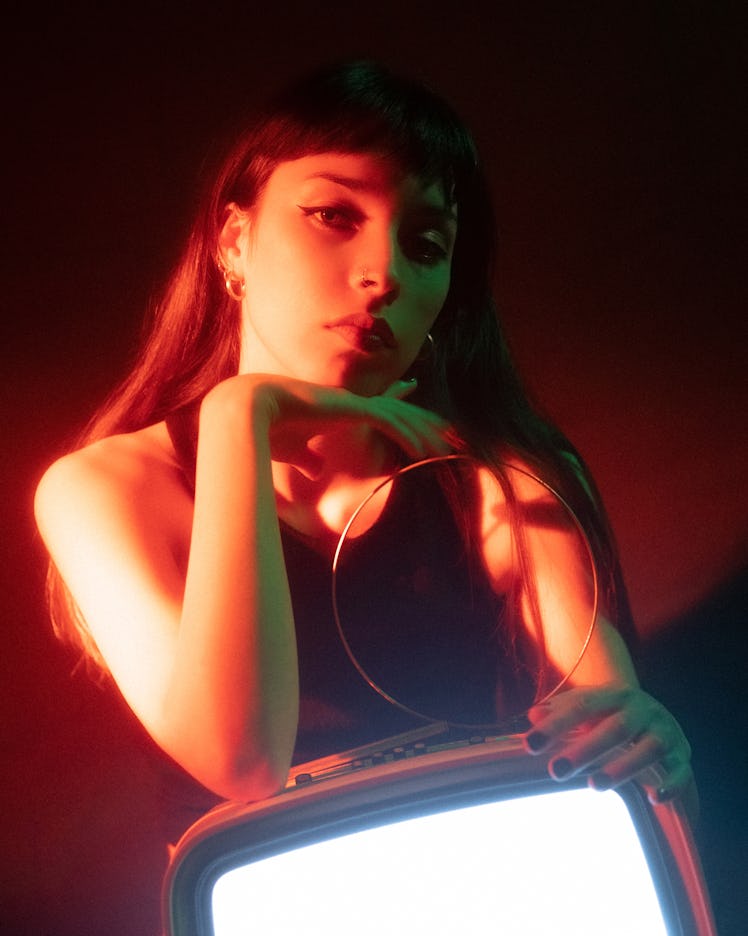 portrait of a young woman holding a lit-up monitor as she considers the spiritual meaning of the jan...