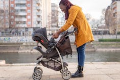 Black mom pushing a baby stroller outdoors during beautiful sunny day