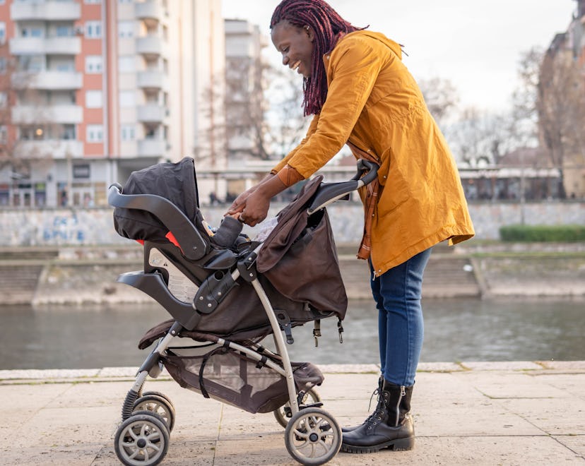 Black mom pushing a baby stroller outdoors during beautiful sunny day