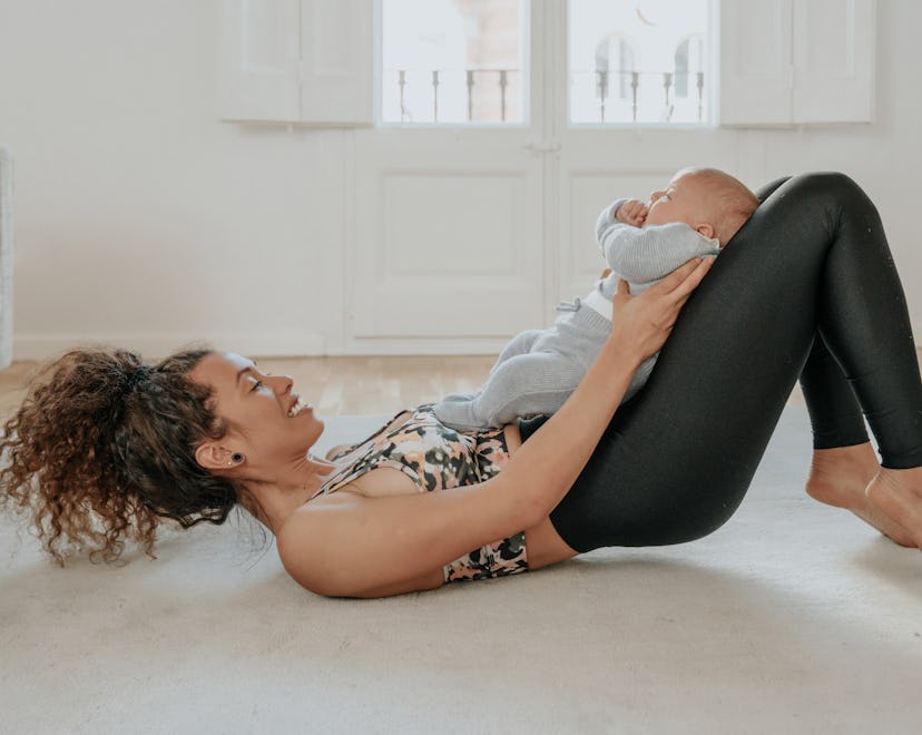 Mom exercises with baby at home, in a story about exercises to relieve postpartum back pain.