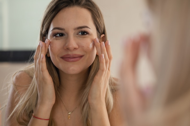 woman applying facial cream to her cheeks