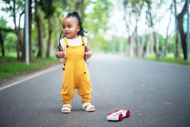 Le portrait mignon de petite fille était intéressé à jouer avec la voiture de jouet en bois dans le parc public dans l'article...