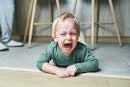 一个两岁的金发小男孩躺在地板上，歇斯底里地哭着……