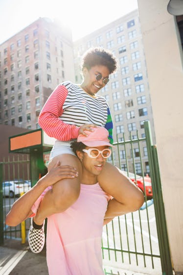 a young man balances his friend, a young woman, on his shoulders as they consider the luckiest day i...