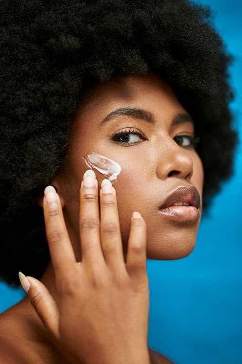 A Black woman applying cream to her skin.