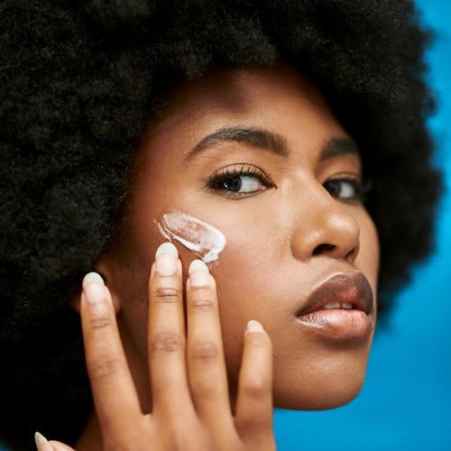 A Black woman applying cream to her skin.