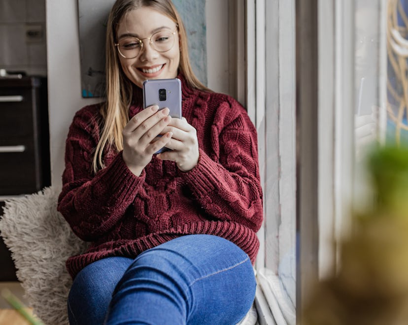Woman smiling and texting someone a Valentine's knock knock joke.