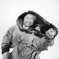 Femme esquimau portant son enfant dans le dos enveloppé dans une peau de caribou, en Alaska, Etats-U...