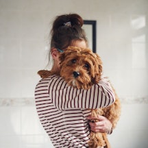 Woman holding her puppy over the shoulder