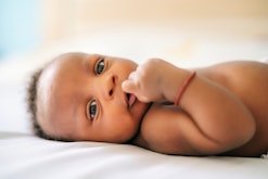 closeup of adorable black newborn baby laying on bed for article on baby girl names that start with ...