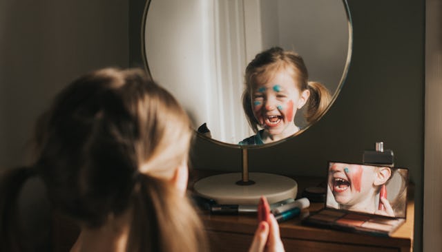 Cute young girl playing at a vanity table, applying various make up products.