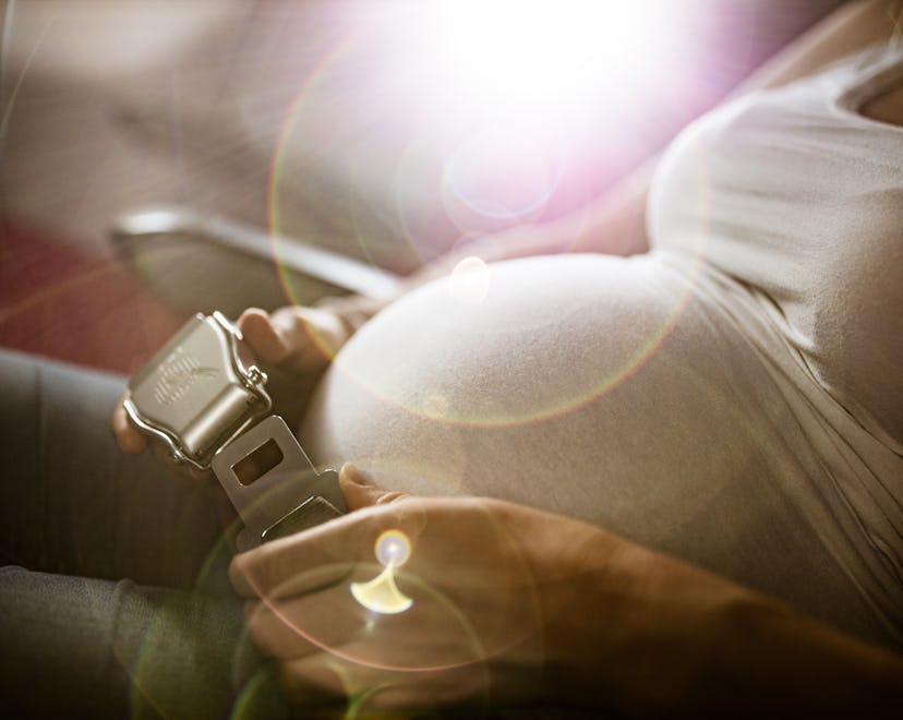 Close up of expecting woman fastening seatbelt before flying during pregnancy.