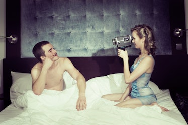 Retro styled image of a young couple having fun with home videoing.
